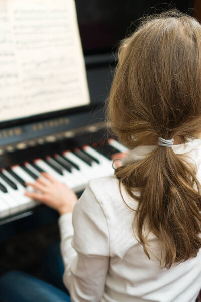 Little girl learning to play the piano.