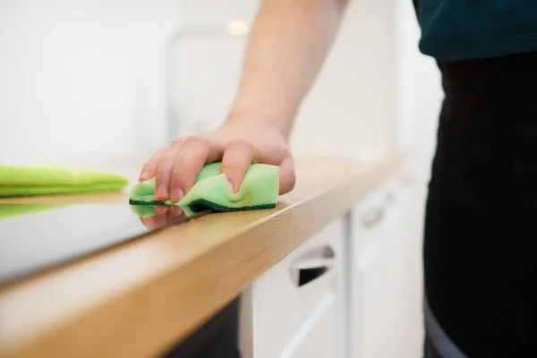 Cleaning service concept. Man cleaning kitchen furniture.