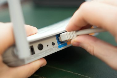 İnternet kablosunu kablosuz yönlendiriciye takan adam.