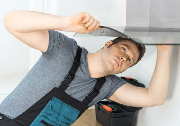 キッチンの排気フードを固定ハンサムな職長 — ストック写真