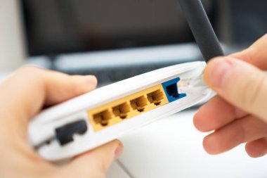 İnternet kablosunu kablosuz yönlendiriciye takan adam.