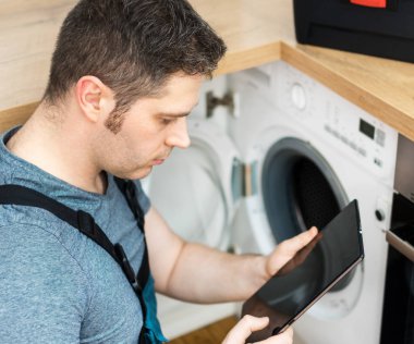 Çamaşır makinesi mutfak incelemesini yaparken el işleri ustası.