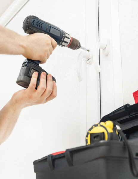 Professional handyman fixing window handle at home.