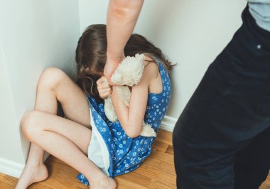 Küçük kız oyuncakla köşede ağlamaya. Aile içi şiddet kavramı.