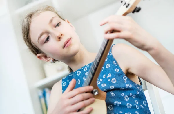 可爱的女孩学习玩四弦琴在家里 — 图库照片