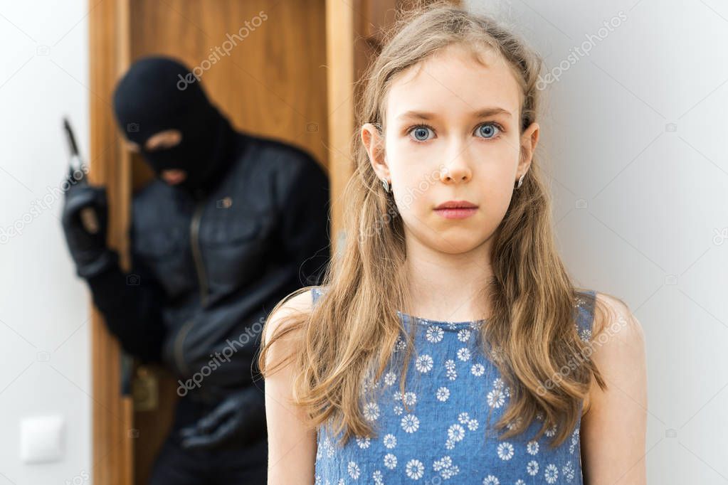 Shocked little girl and angry robber with gun in the background.