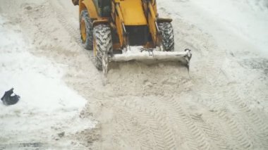 Sokakta kar kürekle traktör.