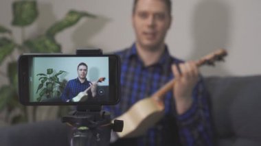 Yakışıklı adam müzik aletleri hakkında video blogu yapıyor..