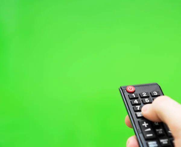 Mężczyzna dłoni z pilota telewizora na zielonym ekranie. Miejsce na Twoją reklamę. — Zdjęcie stockowe