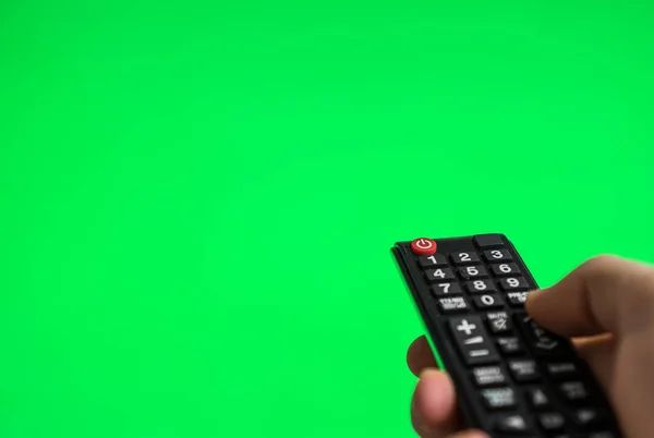 Male hand with TV remote control over green screen. Place for your advertisement. — Stock Photo, Image