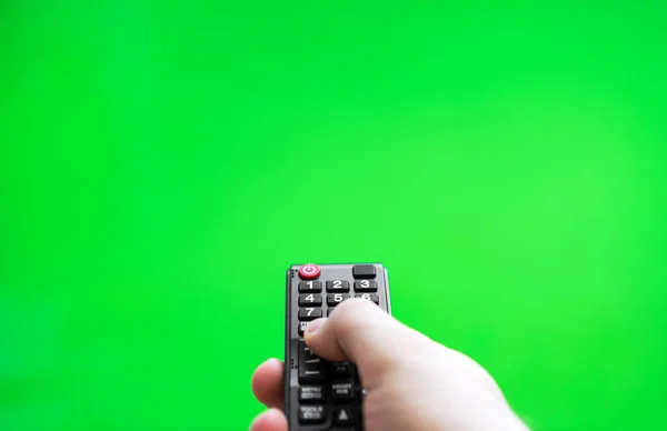 Mężczyzna dłoni z pilota telewizora na zielonym ekranie. Miejsce na Twoją reklamę. — Zdjęcie stockowe