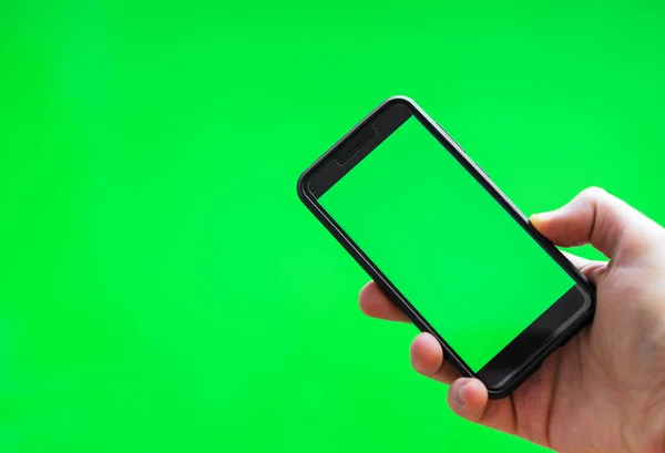 Male hand with Smartphone over green screen. Place for your advertisement. — Stock Photo, Image