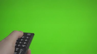 Uzaktan kumanda ile erkek el üzerinde yeşil ekran televizyonu açıyor. Reklam için yer.