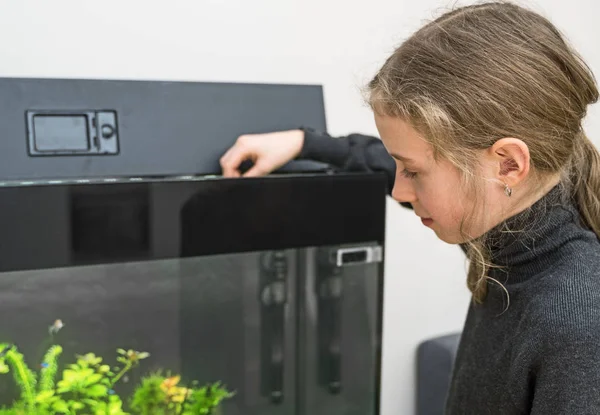 Petite fille nourrissant des poissons dans l'aquarium . — Photo