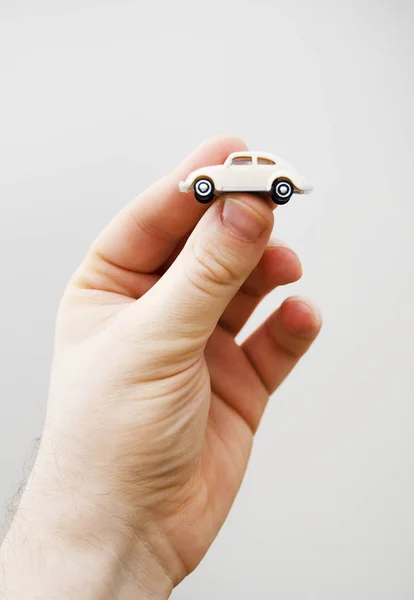 Male hand holding small car toy. Place for text.
