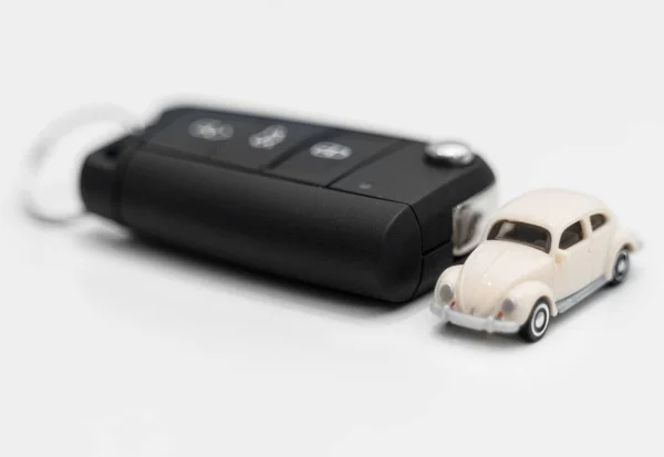 Chiave auto con giocattolo auto su sfondo bianco . — Foto Stock