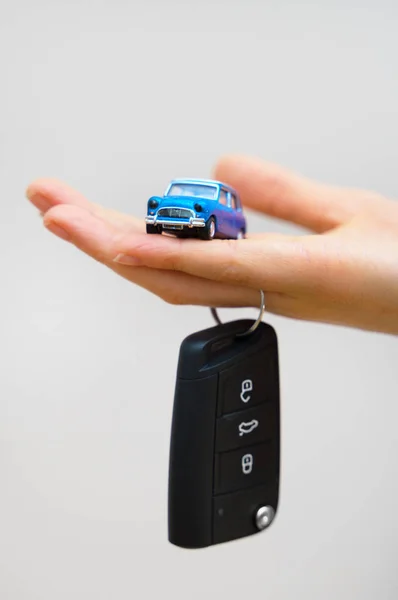 Ruce drží malé auto hračka a klíče. Koncepce nákupu vozu. — Stock fotografie