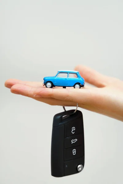 Mão segurando brinquedo de carro pequeno e chaves. Conceito de compra de carro . — Fotografia de Stock