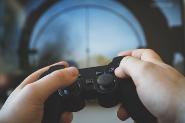 TV 'de atıcı video oyunu oynayan adam. el gamepad denetleyici.