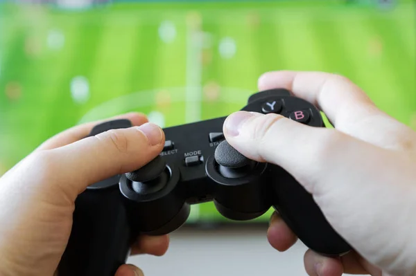 Чоловік грає у футбольну відеогру по телевізору. Контролер Gamepad в руках . — стокове фото