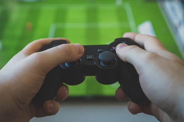 Uomo che gioca ai videogiochi di calcio in TV. Gamepad controller in mano . — Foto Stock