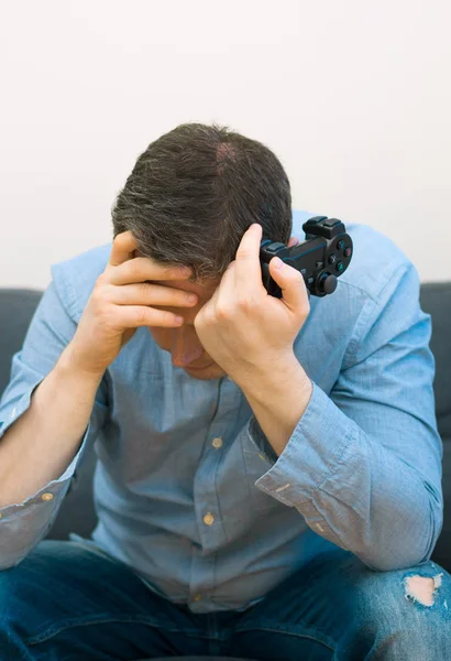 Sad man med gamepad i händer spelar video spel. — Stockfoto