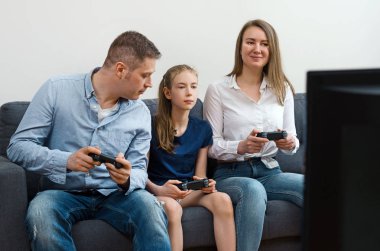 Anne, baba ve kızları evde video oyunu oynuyorlar..