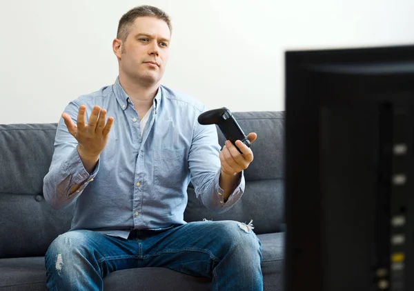 Uomo infelice seduto sul divano con gamepad . — Foto Stock