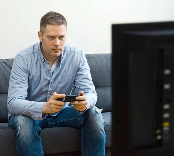 Pohledný muž hraje videohry doma. — Stock fotografie