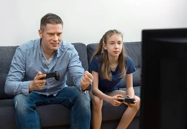 Padre e hija sentados en el sofá con mandos . — Foto de Stock