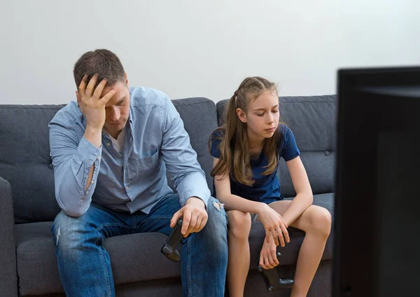 Pai e filha perturbados sentados no sofá com gamepads . — Fotografia de Stock