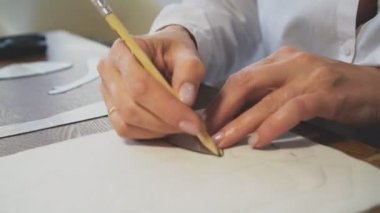 Kadın terzi kalemle maket yapıyor..