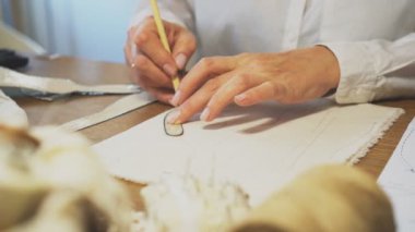 Kadın terzi kalemle maket yapıyor..