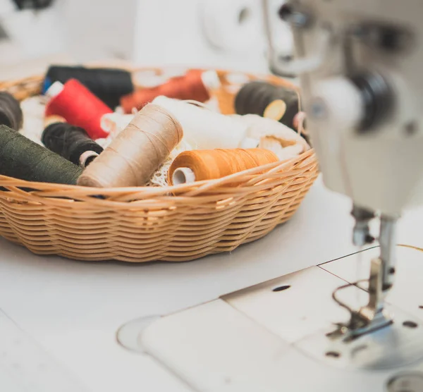 Nähkonzept. viele Fadenspulen neben der Nähmaschine. — Stockfoto