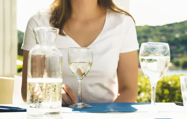 Женщина сидит за столом с белым бокалом вина . — стоковое фото