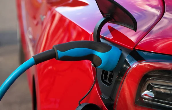 Enchufe eléctrico carga coche eléctrico deportivo rojo . — Foto de Stock
