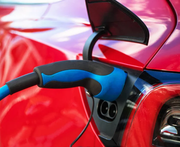 Enchufe eléctrico carga coche eléctrico deportivo rojo . — Foto de Stock