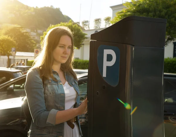 Mulher usando máquina de estacionamento na rua . — Fotografia de Stock