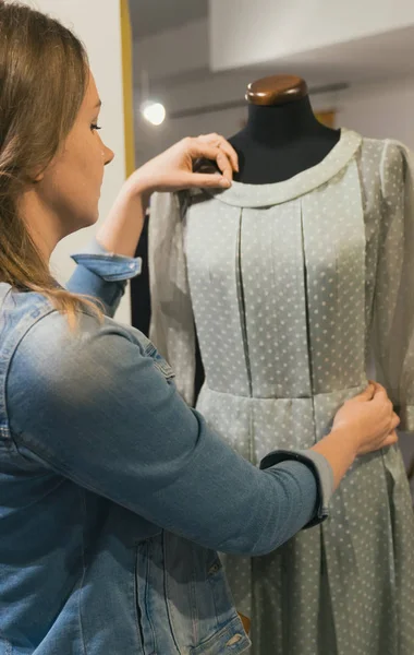 Designer féminin travaillant avec une nouvelle robe de couture modèle sur mannequin en atelier . — Photo