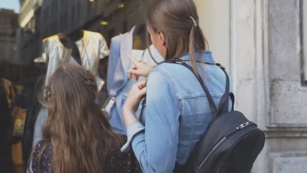 Familj tittar på skyltfönster av klädaffär. — Stockvideo