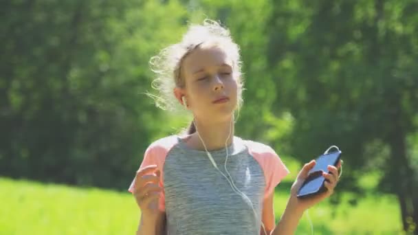 Niña en auriculares escuchando la música al aire libre . — Vídeos de Stock