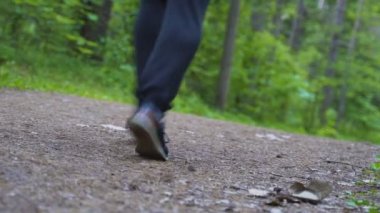 Adam ormanda yol boyunca koşuyor. Kamera aşağıdan vuruyor.