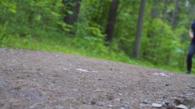 Adam ormanda yol boyunca koşuyor. Kamera aşağıdan vuruyor.