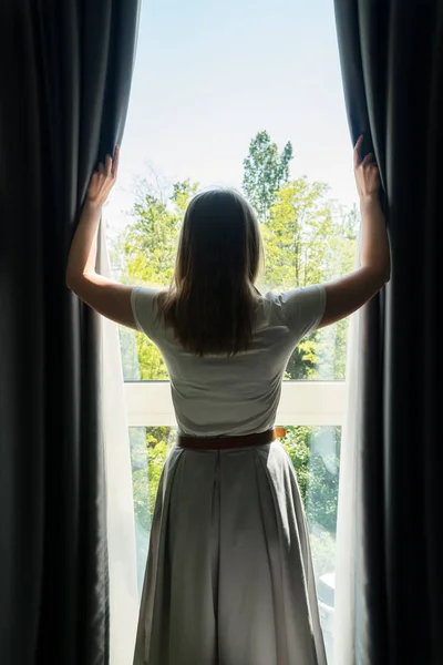 Mujer abriendo cortinas en la habitación del hotel por la mañana . —  Fotos de Stock