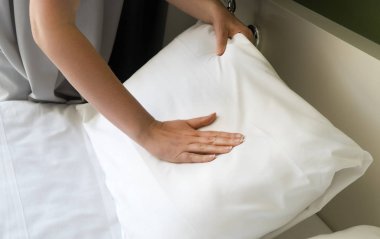 Oda servisi. Otel odasında yatak yapan kadın..