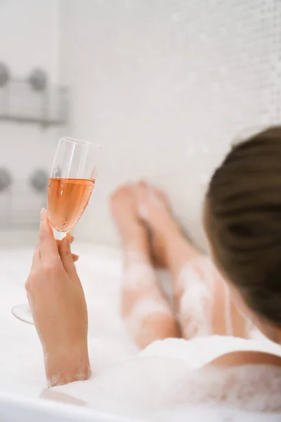 Frau mit Glas Wein entspannt in Badewanne. Rückansicht. — Stockfoto