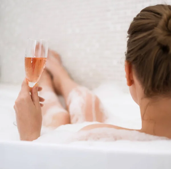 Donna con bicchiere di vino è rilassante nella vasca da bagno. Vista posteriore . — Foto Stock