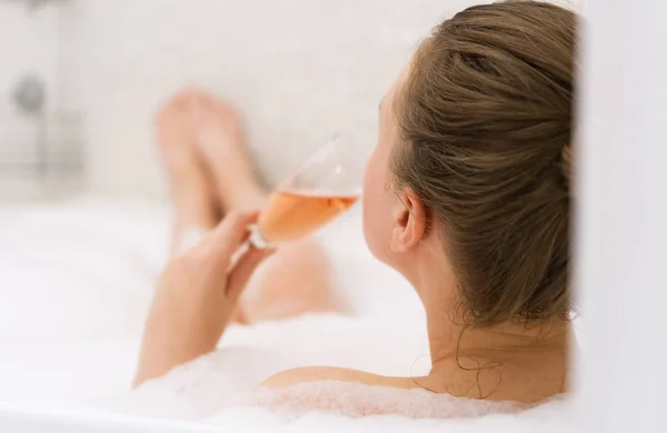 Kobieta z kieliszek wina jest relaks w wannie. Widok z tyłu. — Zdjęcie stockowe