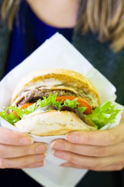 Fast food. Taze pişmiş burger tutan kadın.