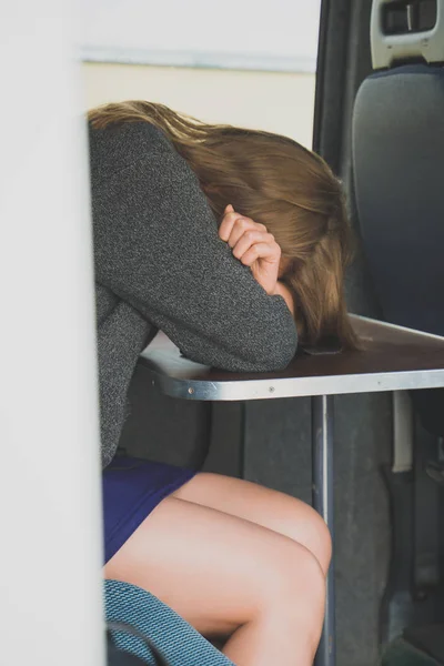 Female criminal sitting in police van and covers her face with her hand. — Stock Photo, Image